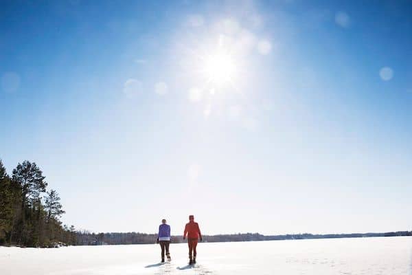 Two people walk across a snow-and-ice-covered Burntside Lake.